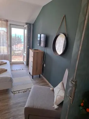 a living room with a couch and a mirror at LaRenta Стилни апартаменти с 2 спални и гледка море в Свети Влас in Sveti Vlas