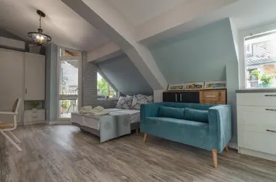 a living room with a blue couch and a bed at Bella in Nesebar