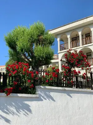 a building with red flowers in front of a fence at Kambani 1 Apartment in Sveti Vlas