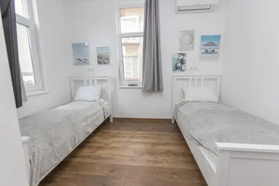 two beds in a room with two windows at The Central House 1 in Burgas City