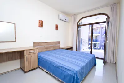 a bedroom with a bed and a desk and a window at Апартаменти за гости ГАРДЪН БИЙЧ in Chernomorets