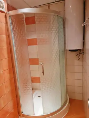 a shower with a glass door in a bathroom at Апартаменти за гости ГАРДЪН БИЙЧ in Chernomorets