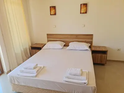 a bedroom with a bed with two towels on it at Апартаменти за гости ГАРДЪН БИЙЧ in Chernomorets