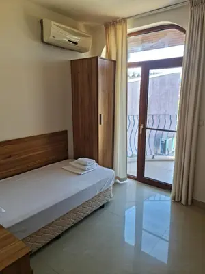 a bedroom with a bed and a sliding glass door at Апартаменти за гости ГАРДЪН БИЙЧ in Chernomorets