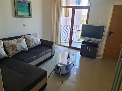 a living room with a couch and a tv at Апартаменти за гости ГАРДЪН БИЙЧ in Chernomorets