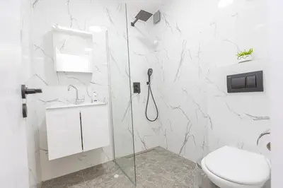 a white bathroom with a shower and a toilet at The Central House 2 in Burgas City