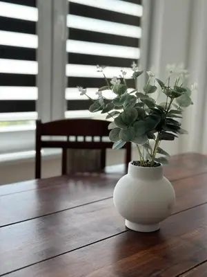 a white vase with flowers on a wooden table at Victoria in Varna City