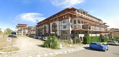 a large building with cars parked in a parking lot at Helios Seaview Apartment in Sveti Vlas