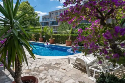 a swimming pool with chairs and purple flowers at Sea Vista Hotel in Sveti Vlas