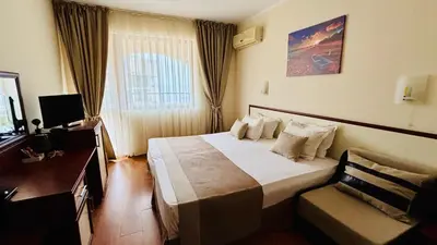 a hotel room with a large bed and a chair at Sea Vista Hotel in Sveti Vlas