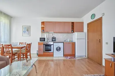 a kitchen and dining room with a table and a kitchen with a stove at Charming 1-Bedroom Apartment in Ravda by Flat Mаnаger in Nesebar
