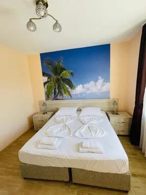 a bedroom with a bed with a palm tree in the background at Garmanovi Apartment in Sozopol, with free parking in Sozopol