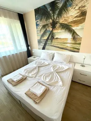 a bedroom with a white bed with a palm tree mural at Palms Studio in Sozopol, with free parking in Sozopol