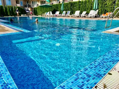a large blue swimming pool with chairs in it at Апартамент Vip Vision Studio LUX in Sunny Beach