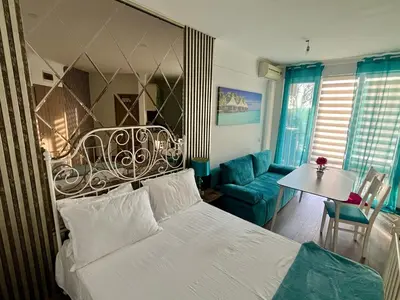 a bedroom with a white bed and a blue couch at Апартамент Vip Vision Studio LUX in Sunny Beach