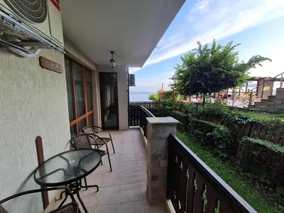 a balcony with a table and chairs and the ocean at Апартаменти в Комплекс Трявна Бийч in Sveti Vlas