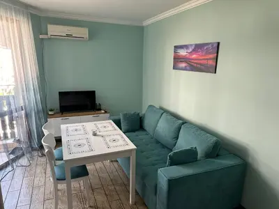 a living room with a blue couch and a table at Апартаменти в Комплекс Трявна Бийч in Sveti Vlas