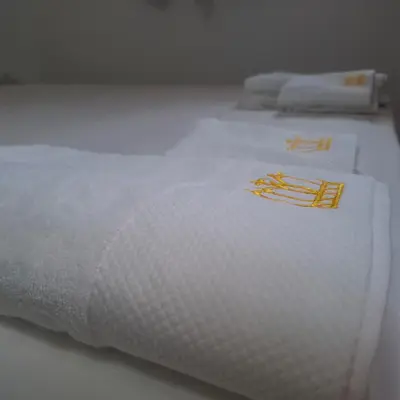 a white bed with white sheets and orange writing on it at Отличен Двустаен Апартамент in Primorsko