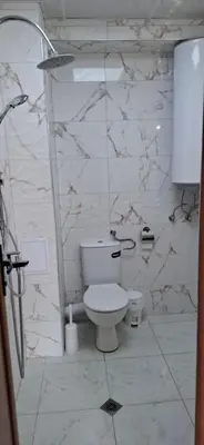 a bathroom with a toilet and a marble wall at Отличен Двустаен Апартамент in Primorsko
