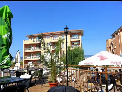 a hotel with tables and umbrellas in front of a building at Studio in Sunny day 6 complex in Sunny Beach