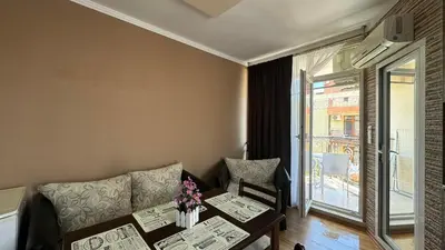 a living room with a table and a couch and a window at Bratanov Bahami Residence Studio in Sunny Beach