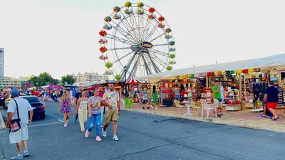 a group of people walking through a carnival with a ferris wheel at Bratanov Bahami Residence Studio in Sunny Beach