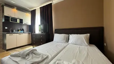 a bedroom with a bed with white sheets and a kitchen at Bratanov Bahami Residence Studio in Sunny Beach