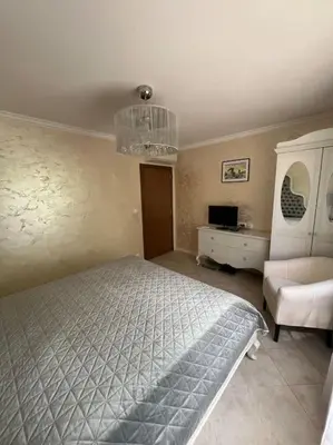 a bedroom with a bed and a white chair at 2 Apartment Verano Del Mar Sozopol in Sozopol