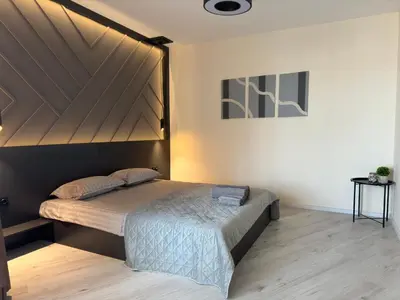a bedroom with a bed with a wooden headboard at South Bay Luxury Apartment in Varna City