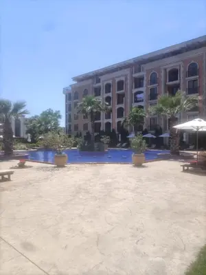 a large courtyard with palm trees and a building at Cascadas Victory Suite Ravda in Ravda