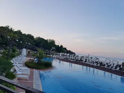 a swimming pool with white lounge chairs and the ocean at Bogdanov in Lozenets
