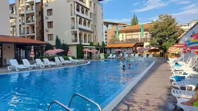 a large swimming pool with chairs and people in the water at Rose Village Private Apartment in Sunny Beach