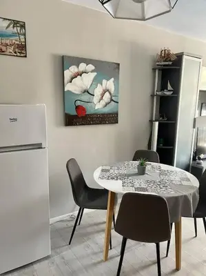 a dining room with a table and chairs and a refrigerator at Апартамент за нощувки в ЕЛИТ 4 Слънчев бряг in Sunny Beach