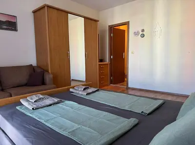a room with a bed and a couch and a mirror at Апартамент за нощувки в ЕЛИТ 4 Слънчев бряг in Sunny Beach