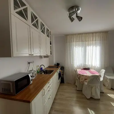 a kitchen with white cabinets and a microwave and a table at Sun Holidays Byala in Byala