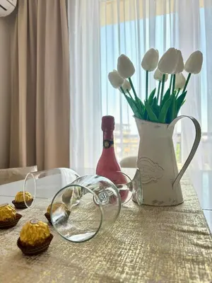 a table with a vase of flowers and a bottle of wine at Triumph apartment in Burgas City