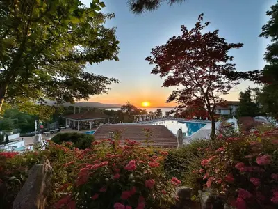 a sunset over a swimming pool with flowers at Apartment Anastasia Santa Marina in Sozopol