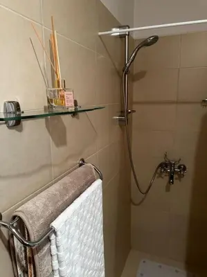 a bathroom with a shower with a towel and a glass shelf at Apartment in Paradise View complex in Sozopol