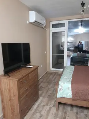 a bedroom with a bed and a flat screen tv at студио Орхидея Сарафово лукс с изглед към морето in Burgas City