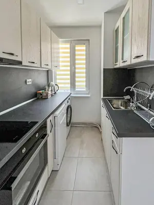 a kitchen with white cabinets and black counter tops at Апартамент Tiana in Tsarevo