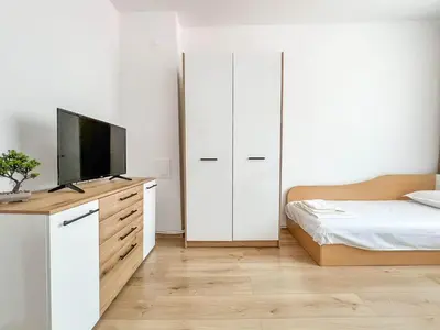 a bedroom with a bed and a tv on a dresser at Апартамент Tiana in Tsarevo