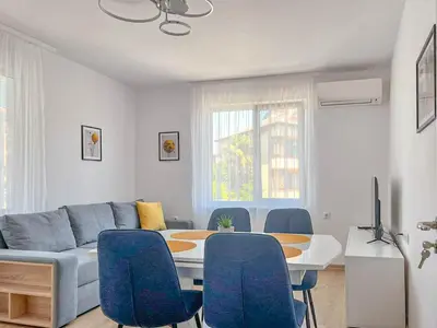 a living room with a couch and a table and chairs at Апартамент Tiana in Tsarevo