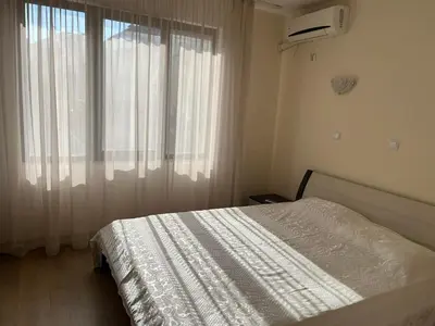 a bedroom with a white bed and a window at На гости в Созопол in Sozopol