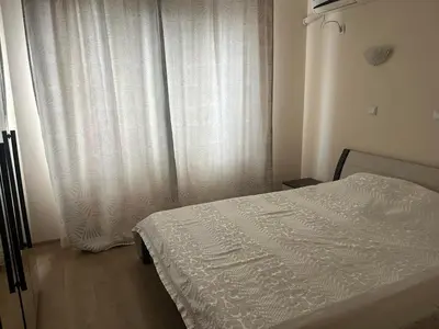a bedroom with a bed and a white curtain at На гости в Созопол in Sozopol