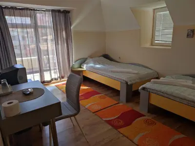a room with two beds and a table and a chair at Апартамент с уникална панорама Несебър in Nesebar