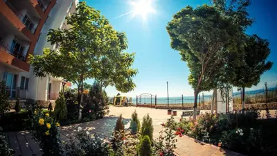 a garden with trees and flowers in front of a building at Riviera Fort Beach Apartment in Ravda
