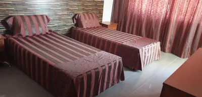 two beds in a hotel room with red curtains at California complex in Sunny Beach