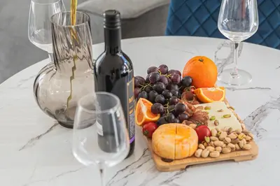 a plate of fruit on a table with a bottle of wine at Royal Bay Apartaments - Sveti Vlas in Sveti Vlas