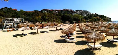 a beach with many straw umbrellas and lounge chairs at Elegant Apartment Artur in Sveti Vlas