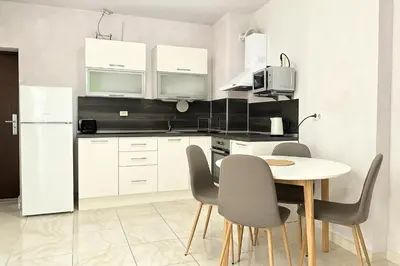 a kitchen with white cabinets and a table and chairs at Elegant Apartment Artur in Sveti Vlas